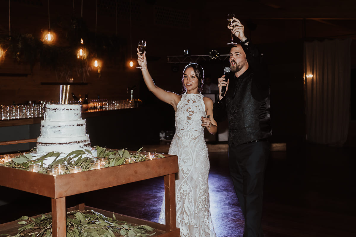 Los novios cortando el pastel rodeados de amigos y familiares